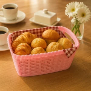 Pink bread basket with croissants, muffins, and snacks on breakfast table
